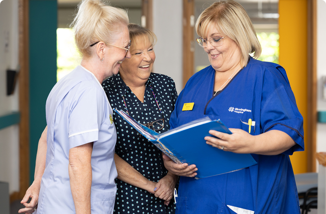 A nurse holding a binder with two people